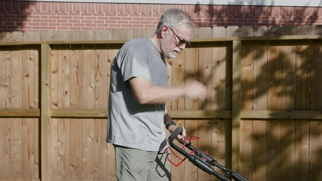 senior man cutting grass suffering from dehydration