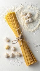 Overhead view of uncooked spaghetti and gnocchi with flour on white background