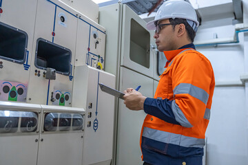Electrical engineers and technicians work together to solve electrical system failures in industrial control rooms.supervisor maintains the circuit cabinet.