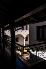 Obraz premium Sunlight illuminating tables in a courtyard seen from a dark balcony
