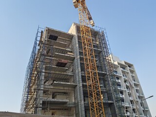 Under construction residential building with Concreate Block structure and Fixed Tower Crane.
Exterior view Highrise Multistory Tower modern design Yellow Tower Crane and erected Scaffolding Around