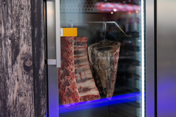 Dry-aged meat displayed in a modern refrigerated cabinet at a butchery shop