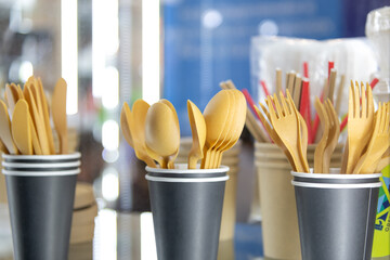 Biodegradable plastic utensils displayed in cups at a sustainable market event