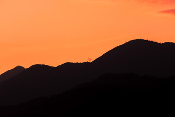 Beautiful sunset on orange sky over mountains background. Summer sunset. The mountains are clearly visible as beautiful silhouettes.