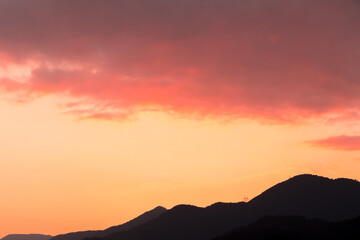 Obraz premium Beautiful sunset on orange sky over mountains background. Summer sunset. The mountains are clearly visible as beautiful silhouettes.