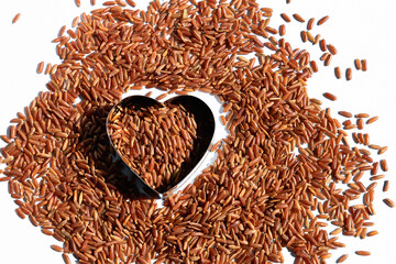 Heart-shaped on healthy uncooked raw red rice. Food for a healthy heart and blood vessels. High...