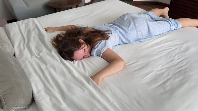 Tom Lada girl lies and falls asleep on a white bed waving her arms sleeping on her stomach brown hair teenager fatigue depression