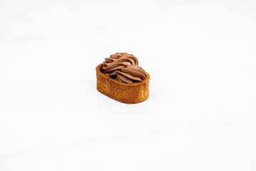 Tartlet with caramelized nuts isolated on white. Tasty dessert. Caramel tartlet, caramelized peanuts, salted caramel, chocolate ganache. Dessert of dough, nut tartlets covered with a layer of caramel