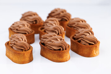Dessert of dough, nut tartlets covered with a layer of caramel. Tartlet with caramelized nuts isolated on white. Caramel tartlet, caramelized peanuts, salted caramel, chocolate ganache. Tasty dessert