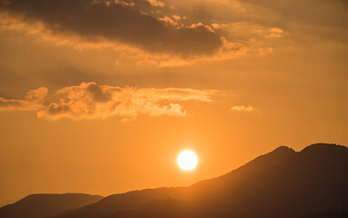Beautiful sunset on orange sky over mountains background. Summer sunset. The mountains are clearly visible as beautiful silhouettes.