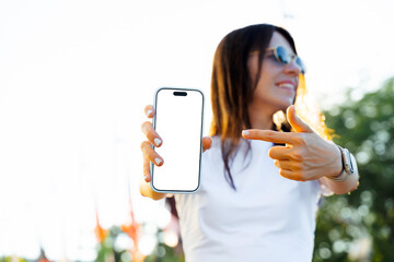 Mockup of smartphone held by woman pointing at screen outdoors