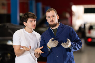 Guy discusses further repairs to his car with car mechanic at a car service center