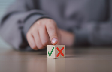 Decision Making and Evaluation Concept. Hand points at wooden cube with green check and red cross...
