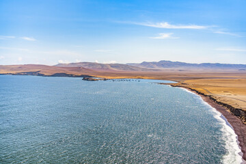 A breathtaking view of Playa Roja, known for its unique red sand and the dramatic cliffs in Paracas Natural Reserve.