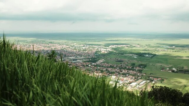Green grass in foreground with town of Vrsac and flat plains fading into the distance, Serbia country. 4k horizontal footage