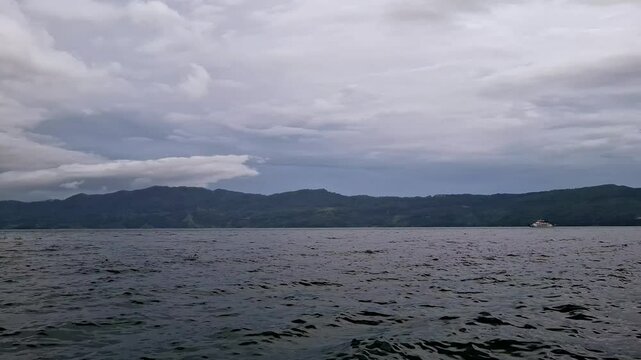 View of the KMP Pora pora ferry sailing on Lake Toba with small waves. Domestic ferry with a fixed route on lake waters. Lake Toba view and activity.