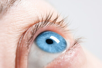 Closeup view of woman with blue eyes on light background