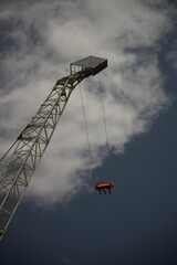 crane with hanging cables seen from below with a partially cloudy sky in the background 