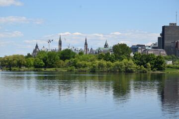 Panorama of tall buildings in downtown Ottawa reflected on the river on a sunny spring day