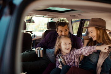 Family road trip enjoying hot drinks in the back of SUV