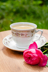A rustic scene with a cup of coffee and a pink rose, ideal for lifestyle and morning themes.