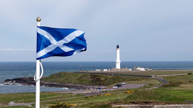 Aerial shot of Scottish flag waving over landscape in Scotland, UK