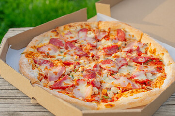 Pizza with sausages in a cardboard box.