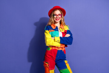 Stylish young woman wearing a colorful denim outfit and smiling with crossed arms against a vibrant...