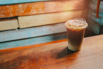 Ice coffee in cafe. Iced coffee in clear cup on wooden table with colorful background of rustic wooden planks in café setting