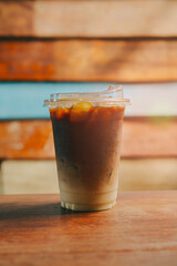 Ice coffee in cafe. Refreshing Iced Coffee Beverage in a Clear Cup with Straws on a Wooden Table Against a Colorful Background