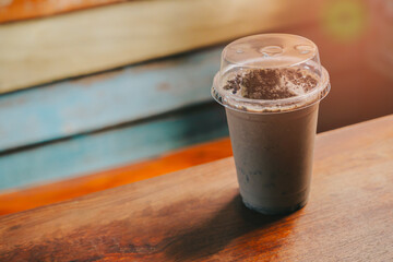 Chocolate Smoothie. Refreshing Chocolate Milkshake in Clear Plastic Cup on Wooden Table in Cozy Café Environment