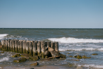 rocky beach with a wooden pier and a pond. The sky is clear and blue. a tourist destination, a...