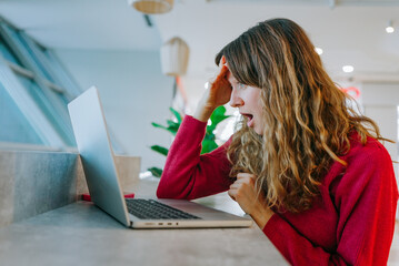 Professional woman showing shock while viewing laptop screen during video call, experiencing...