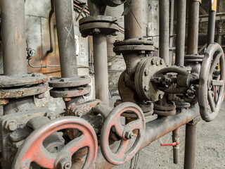 Close-up of rusty shut-off valves and pipelines showing signs of long-term use and natural aging.