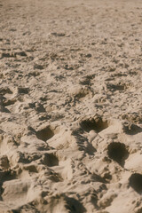chain of footprints in the sand. The footprints of human shoes are arranged in a row and very close to each other, the beach is trampled by feet.