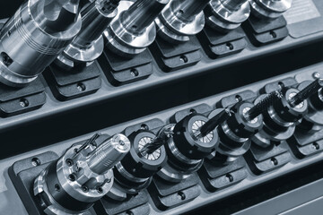 A row of metal tools, milling cutters and drills, are lined up on a shelf. tools are all different...