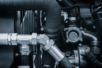 Blue tone engine with a black hose attached to it. The hose is connected to a black pipe