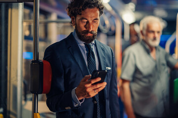 Businessman using smartphone on public transport at night