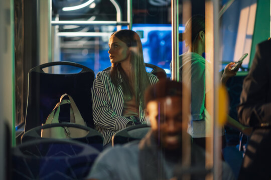 Young woman sitting on bus looking out window at night