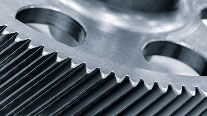 close up gear is made of metal and has lot of teeth. teeth are sharp and pointy, which makes the gear look like it is ready to cut through something, blue tone