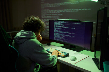 A young programmer codes intently in a dark setting, immersed in his work and creativity