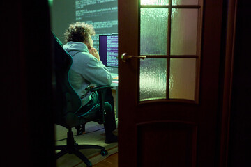 A young programmer codes intently in a dark setting, immersed in his work and creativity