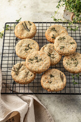 Shortbread cheese cookies with aromatic herbs on cooling rack on rustic textured background. Savory parmesan cookies for party