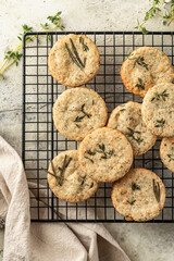 Shortbread cheese cookies with aromatic herbs on cooling rack on rustic textured background. Savory parmesan cookies top view
