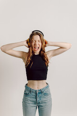 Portrait of a woman with brown hair in a black t-shirt  posing in photo studio with an yellow ear...