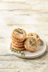 Shortbread cheese cookies with aromatic herbs on white plate on rustic textured background isolated. Savory parmesan cookies for party