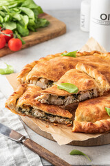 Traditional closed italian pizza calzone stuffed with chicken. mozzarella and spinach on light gray background