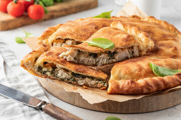 Traditional closed italian pizza calzone stuffed with chicken. mozzarella and spinach on light gray...