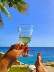 Relaxing on a beach with a good drink in hand. Palm tree leaves and sea in the background. Nice...