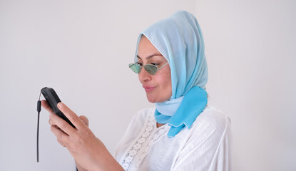Woman in headscarf surfs the internet on smartphone.Muslim people lifestyle